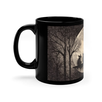 a black coffee mug with an illustration of foxes sitting in front of a full moon in a forest printed on it.